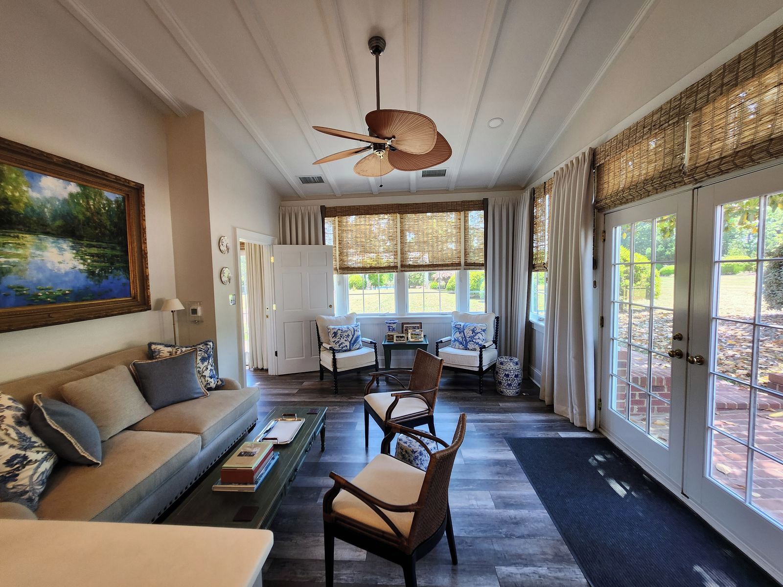 A spacious living area with a sofa, chairs, a coffee table, and a painting on the wall.