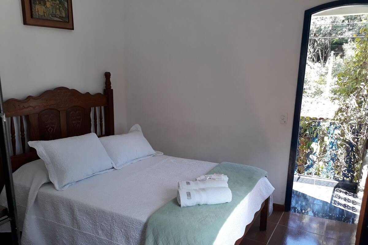 A neatly made bed with a wooden headboard, white linens, and a green blanket.