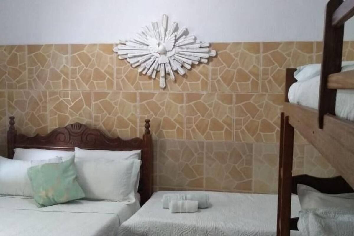 A room with a stone-patterned wall, a wooden bed with a headboard, and a bunk bed.