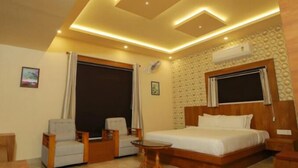 A hotel room with a bed, two armchairs, a small table, and a ceiling with recessed lighting. - White Gate Luxury Hotel (Iritty)