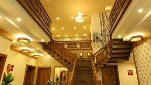 A grand staircase with ornate railings and a chandelier, leading to an upper level. - White Gate Luxury Hotel (Iritty)