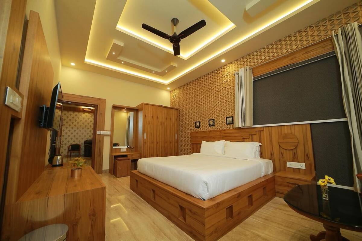 Een moderne hotelkamer met een houten bed, een bureau en een plafondventilator.