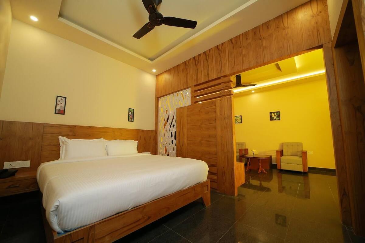 Een hotelkamer met een houten bed, een plafondventilator en een heldergele muur.