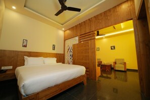 A hotel room with a wooden bed, a ceiling fan, and a bright yellow wall. - White Gate Luxury Hotel (Iritty)