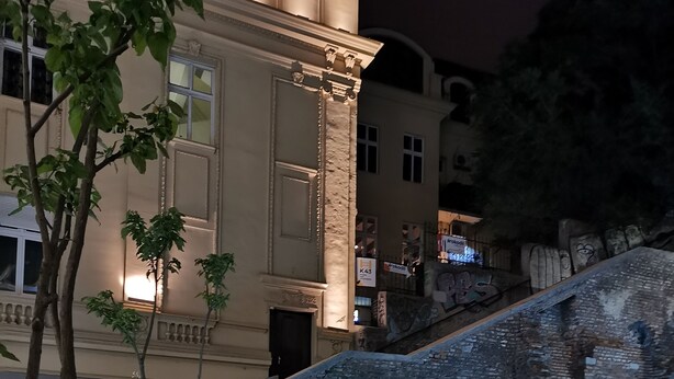 Un espacio exterior moderno con pared de ladrillo, escalones de madera y una zona de estar iluminada.