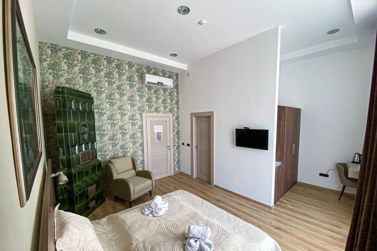 A hotel room with a bed, a chair, a TV, and a wardrobe.