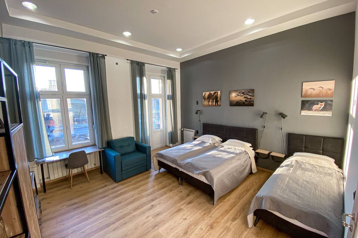 A modern hotel room with two beds, a desk, and a chair.