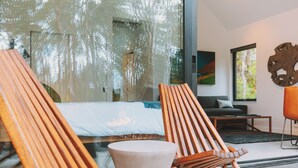 A modern room with a large window, a bed, two wooden chairs, a small table, and a sofa. - Kuono at Volcano   . (Volcano)