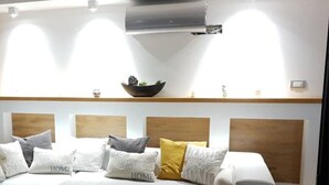 A modern living room with a white sectional sofa, a wooden headboard, and a built-in shelf with decorative items.