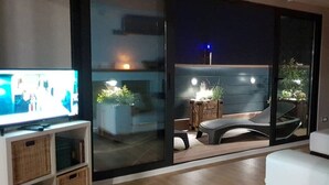 A modern living room with a television, a sofa, and a dining area with a table and chairs.