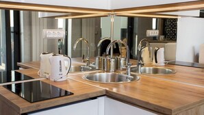 A modern kitchen with a double sink, a kettle, and a coffee maker.