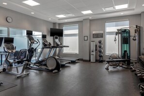 A gym with treadmills, elliptical machines, a weight bench, and exercise balls.