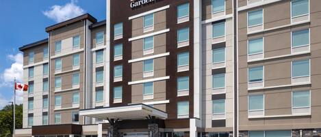 A multi-story Hilton Garden Inn with a modern architectural design, featuring a prominent entrance with a canopy, and a flagpole with a Canadian flag.