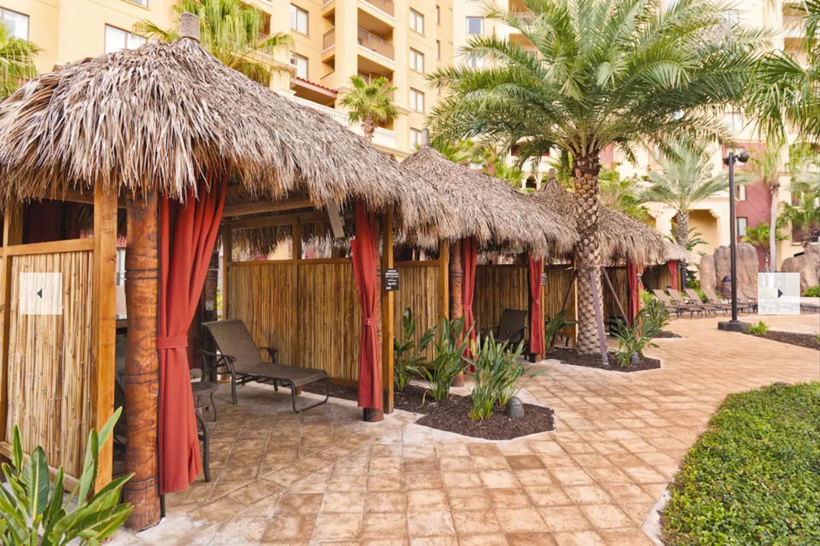A resort with thatched-roof huts, palm trees, and lounge chairs.