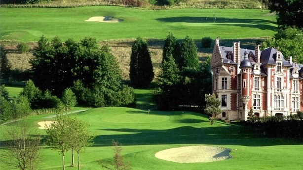 Camp de golf amb búnquers i un edifici gran d'estil arquitectònic tradicional.