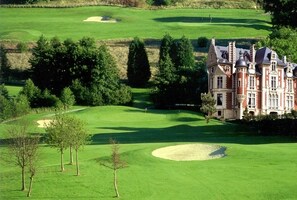 Ein Golfplatz mit Bunkern und einem großen Gebäude im traditionellen Baustil.