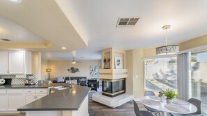 Una cocina moderna con una isla central, una zona de comedor con una mesa redonda y sillas, y una chimenea.