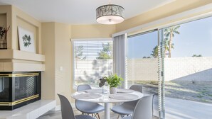 Un comedor moderno con una mesa redonda, sillas grises, una planta en maceta y una chimenea.