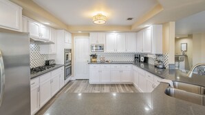 Una cocina moderna con armarios blancos, electrodomésticos de acero inoxidable y encimera de granito.