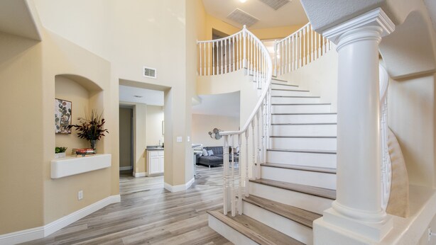 Un interior espacioso con una imponente escalera, una zona de cocina y un área de estar.