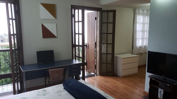 A bedroom with a bed, a desk, a chair, a TV, and a wardrobe.