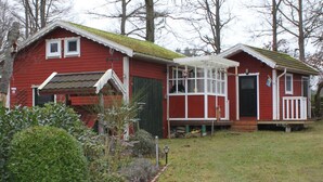 Ein rotes Holzhaus mit weißem Vorbau und einer kleinen angebauten Garage.