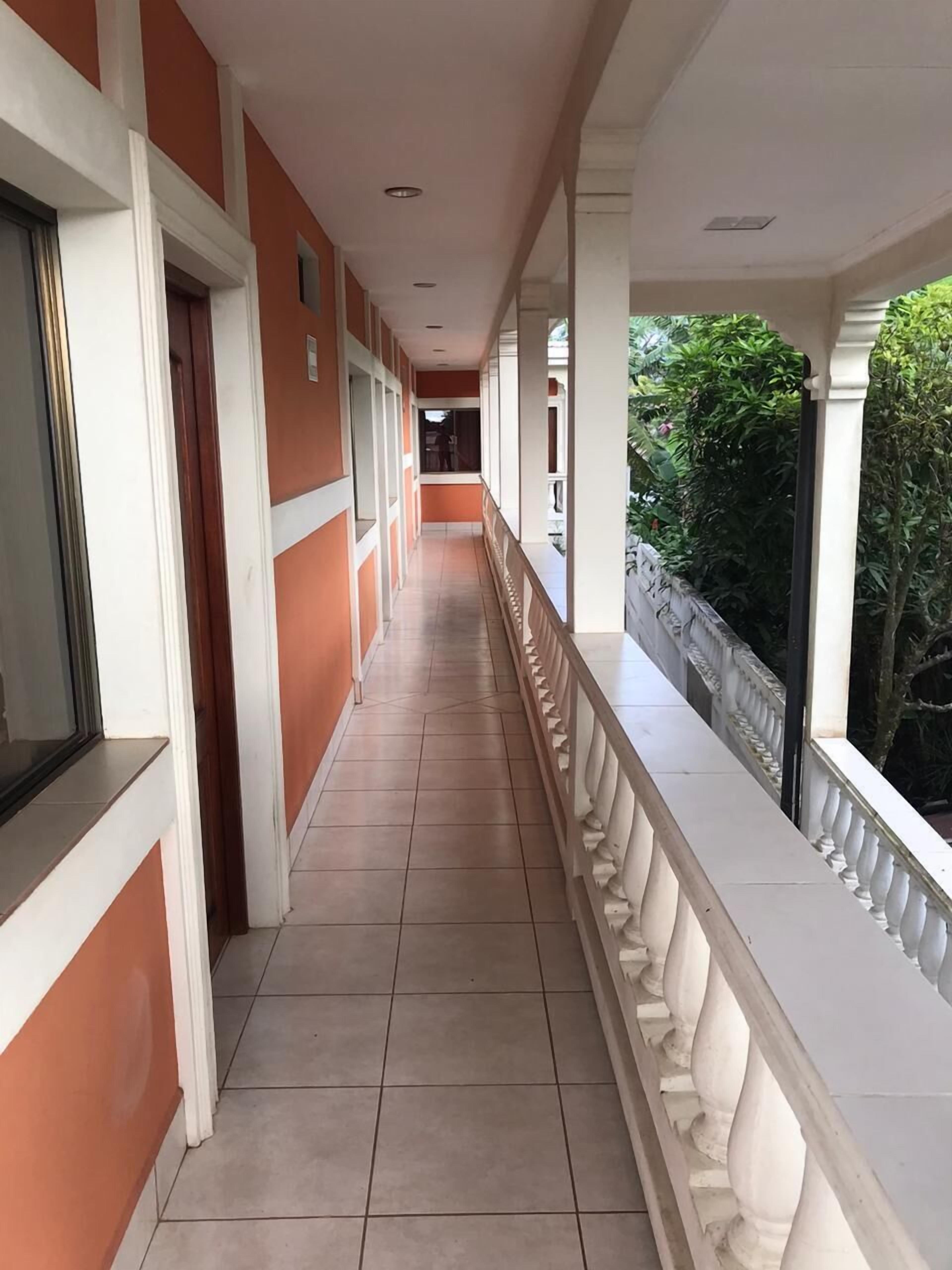 A corridor with a tiled floor, white balustrades, and orange walls.