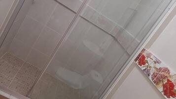 A bathroom with a glass-enclosed shower, a toilet, and a bidet.