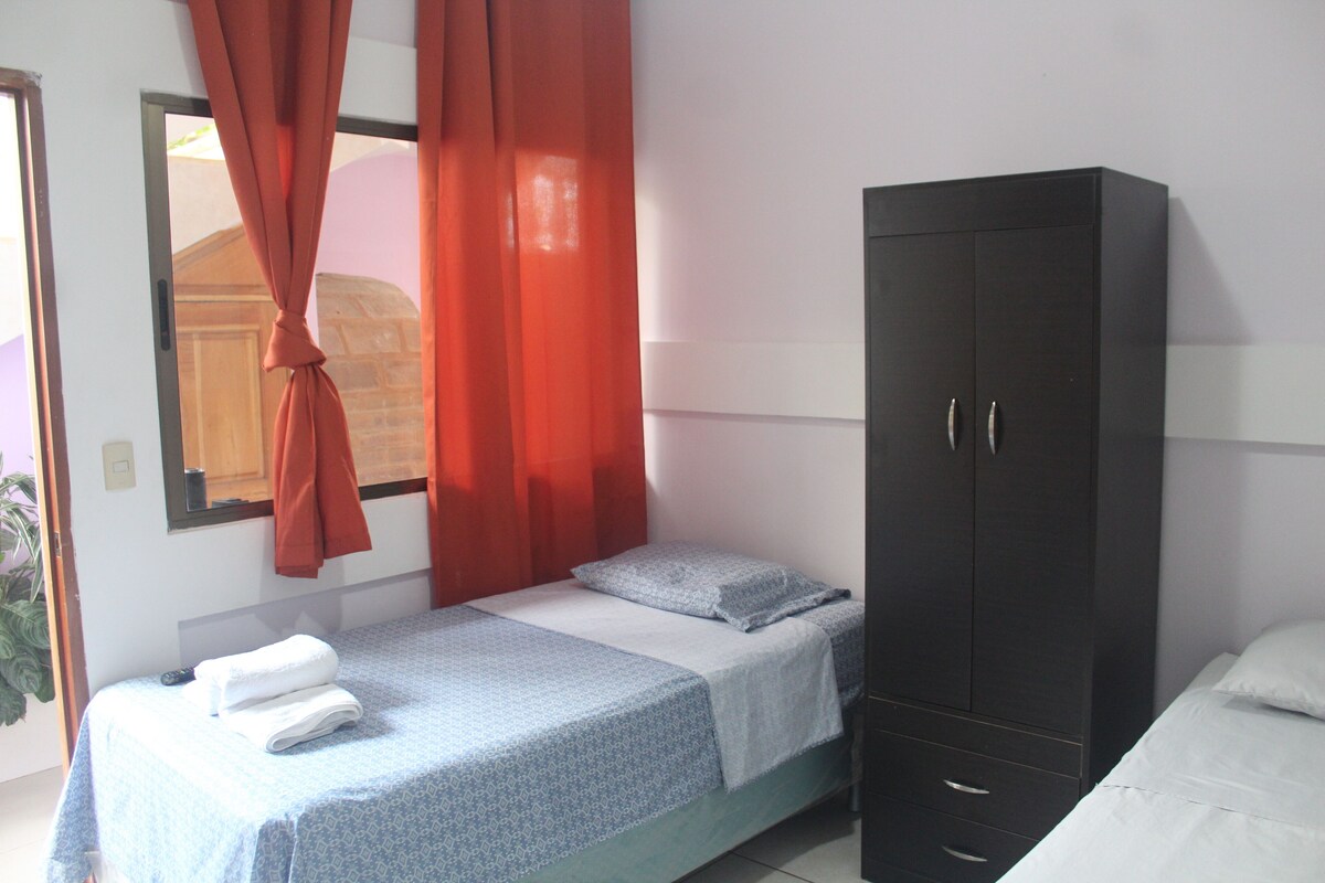 A bedroom with a bed, a wardrobe, and a window with curtains.