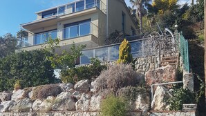 A modern two-story building with a stone retaining wall and a balcony. - Apartment OCEAN AND FOREST VIEWS WITH PRIVATE POOL (2 rooms) (Blanes)