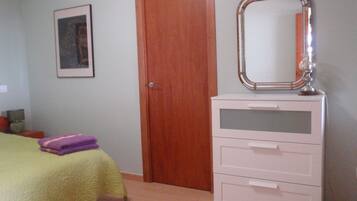 A bedroom with a bed, a dresser, a mirror, and a door.