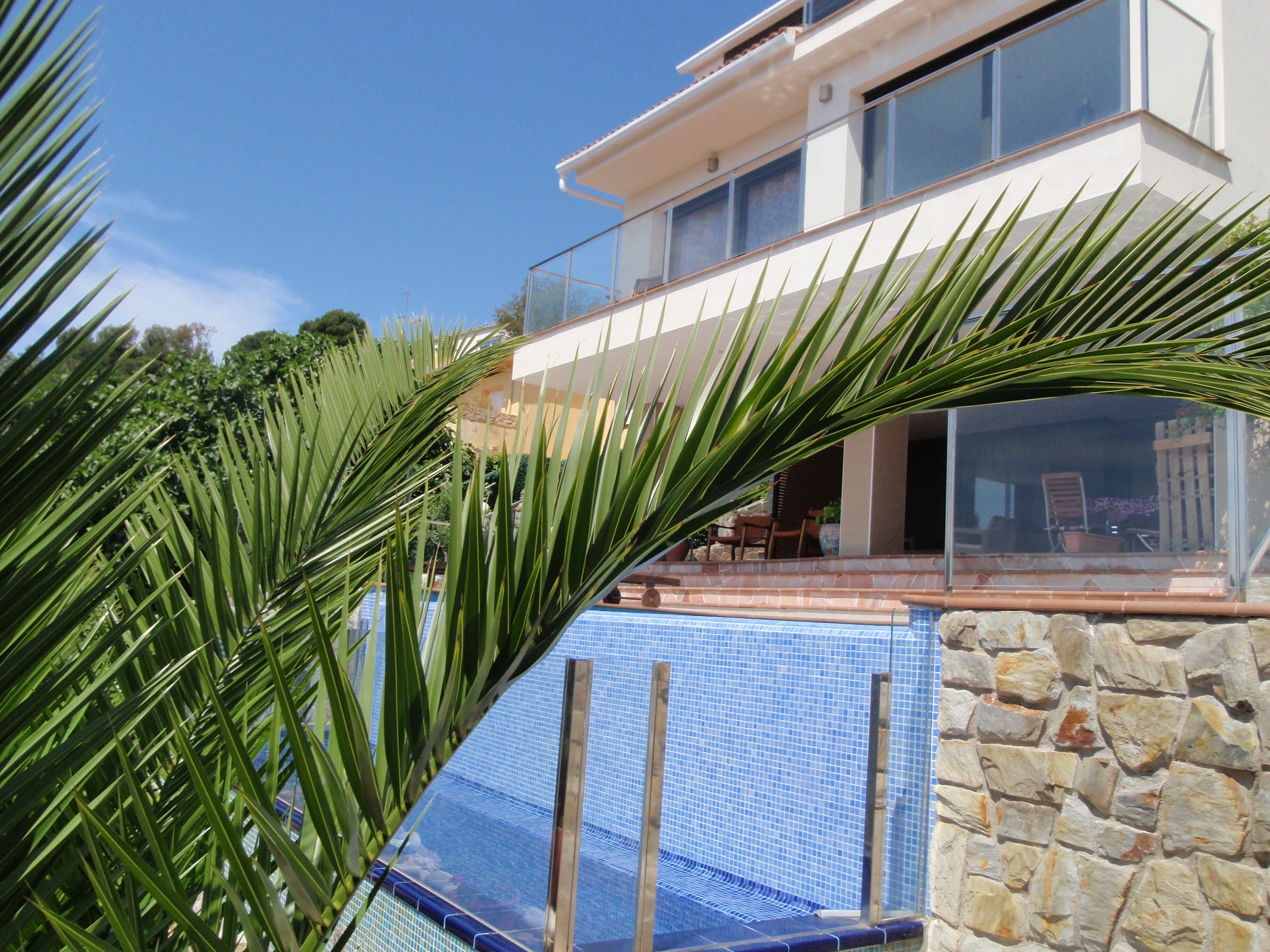 Uma casa moderna com piscina, paredes de pedra e varanda com mobiliário de exterior.