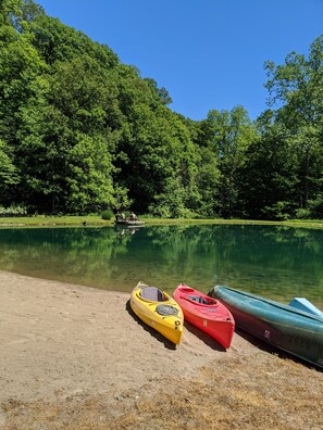 Un lac paisible, bordé de kayaks, entouré d’une forêt verdoyante et dense.