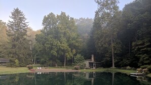 Un cadre paisible au bord d’un lac, avec un petit chalet et des chaises longues installées près de l’eau.