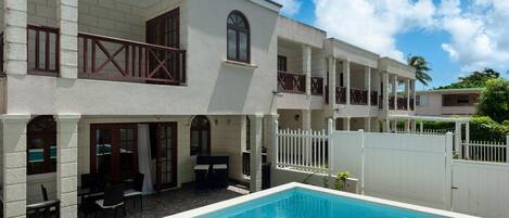 Un bâtiment à deux étages doté d’une piscine, d’un espace extérieur aménagé et d’une clôture blanche.