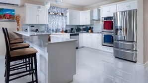 A modern kitchen with white cabinetry, stainless steel appliances, and a central island with bar stools.