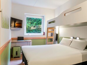 A hotel room with a bed, a desk with a laptop, a window with a view of greenery, and a small stool. - Ibis Budget Bilbao Barakaldo (Barakaldo)