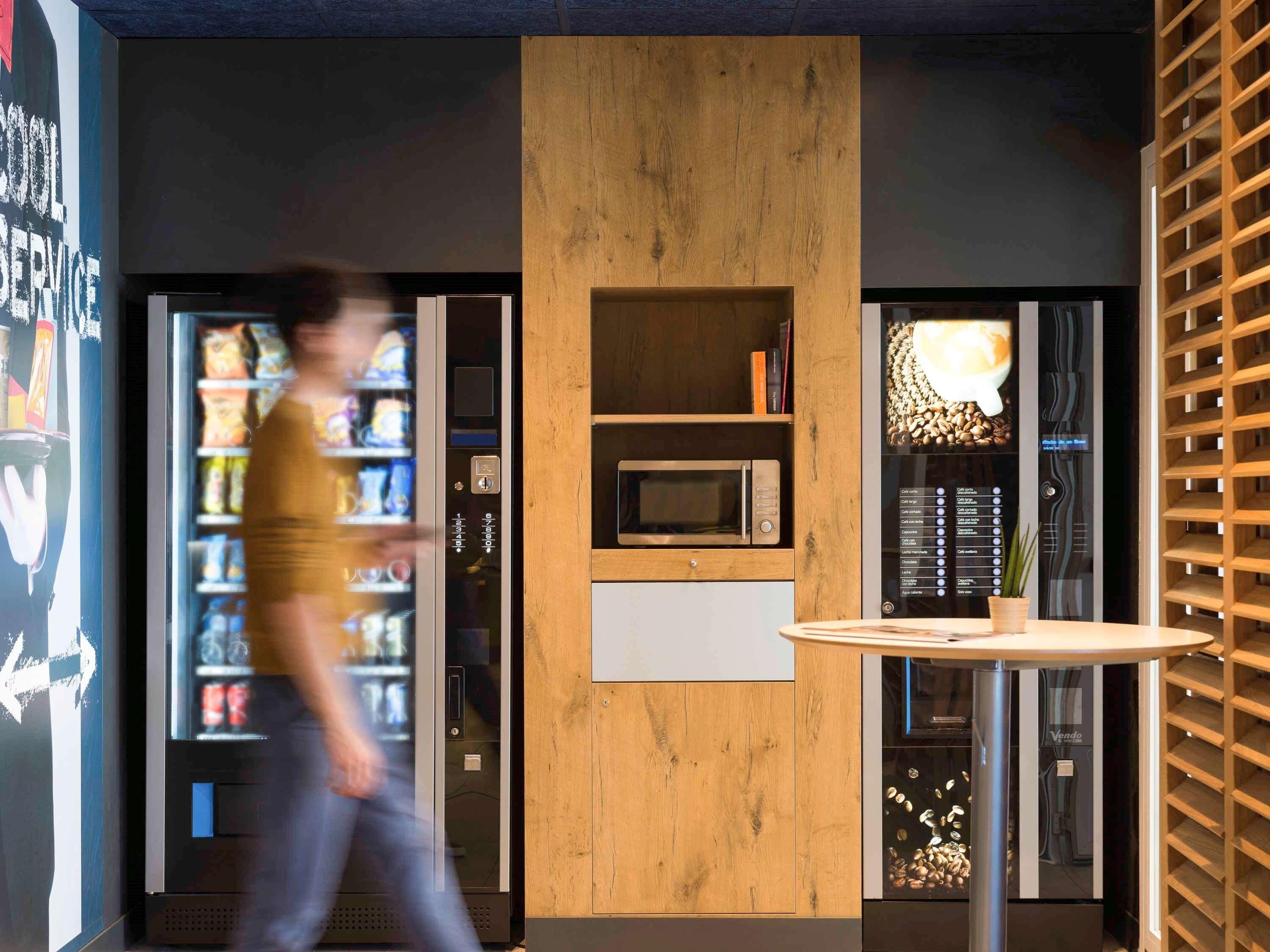 A modern interior with a vending machine, a microwave, and a small table.