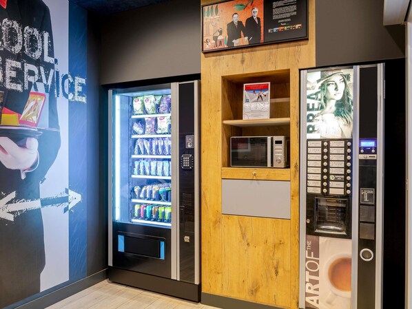 A vending machine area with a microwave and a beverage dispenser.