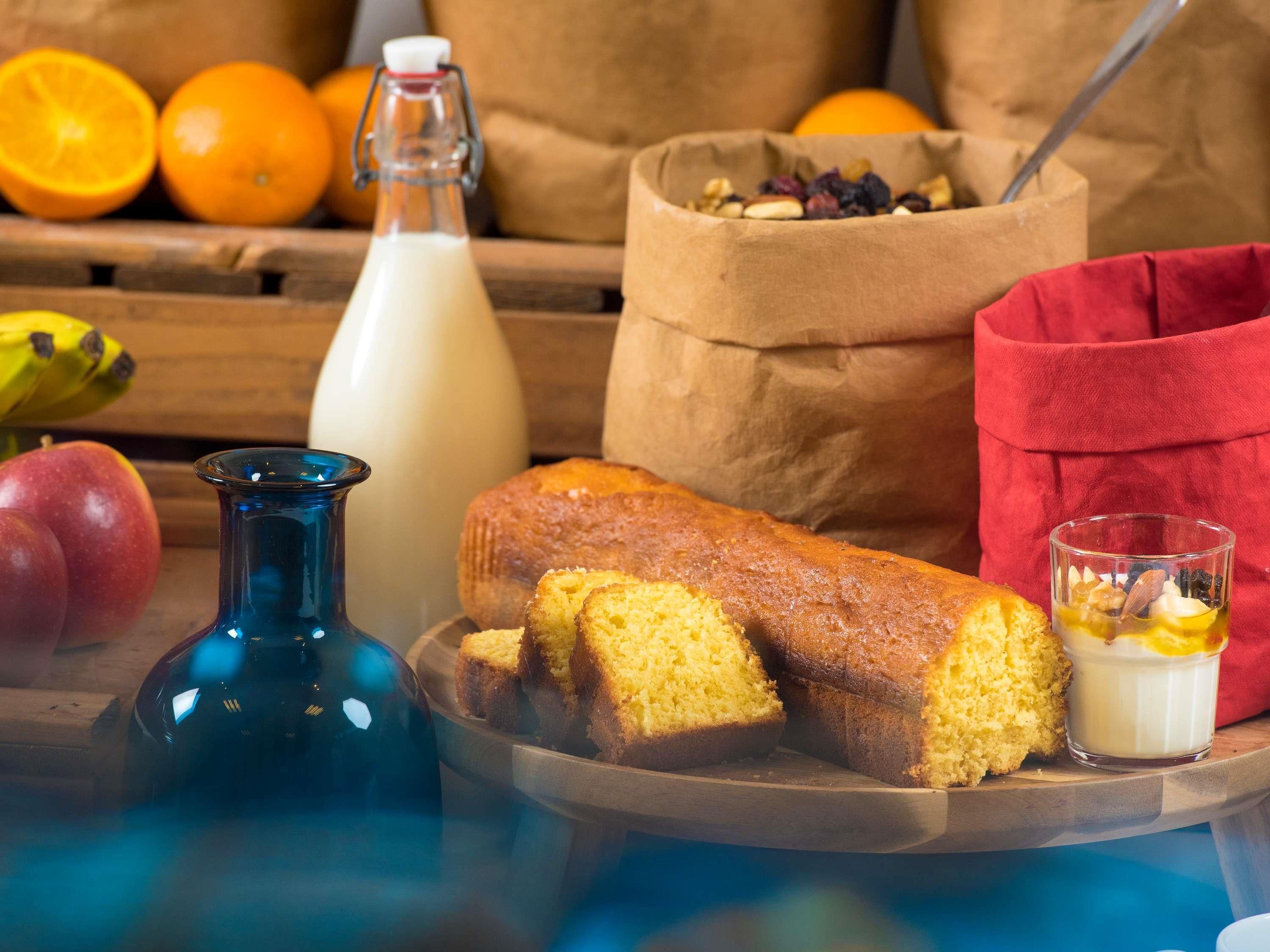 Een brood, een glas melk en een schaal fruit op een houten tafel.