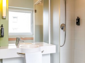 A bathroom with a double sink, a mirror, a shower, and a window. - Ibis Budget Bilbao Barakaldo (Barakaldo)