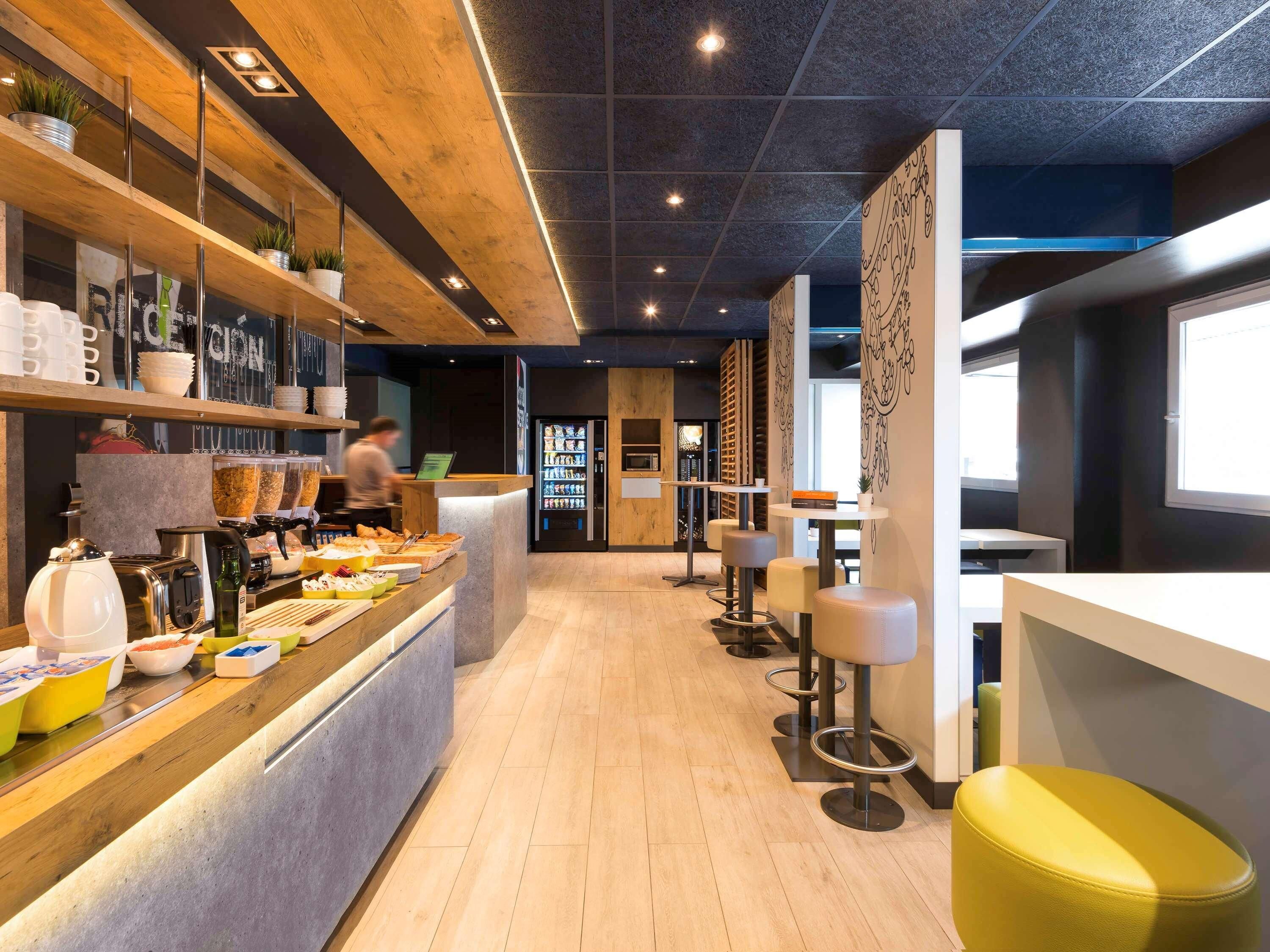 Een modern café-interieur met een houten toonbank, een zithoek en een automaat.