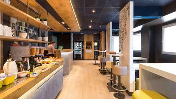 Een modern café-interieur met een houten toonbank, een zithoek en een automaat.