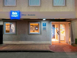 A building with a sign for 'ibis budget' and a 'P' parking sign.