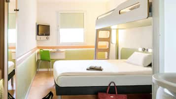 Een compacte hotelkamer met een stapelbed, een bureau met een stoel, een televisie en een raam.