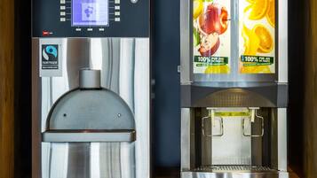 Dos máquinas de café con pantallas digitales y etiquetas con motivos de frutas.