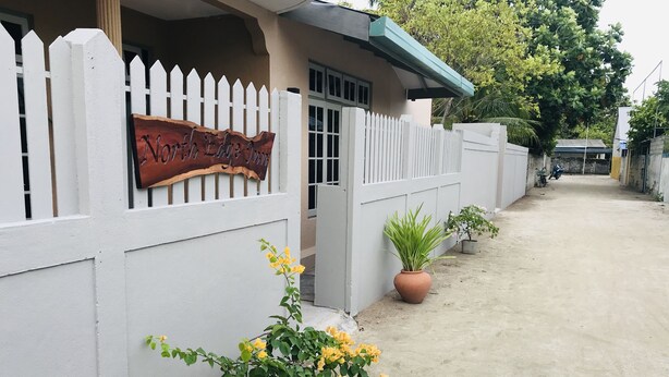 A gated entrance with a sign reading "Northside Edge Inn." There are potted plants along the pathway.