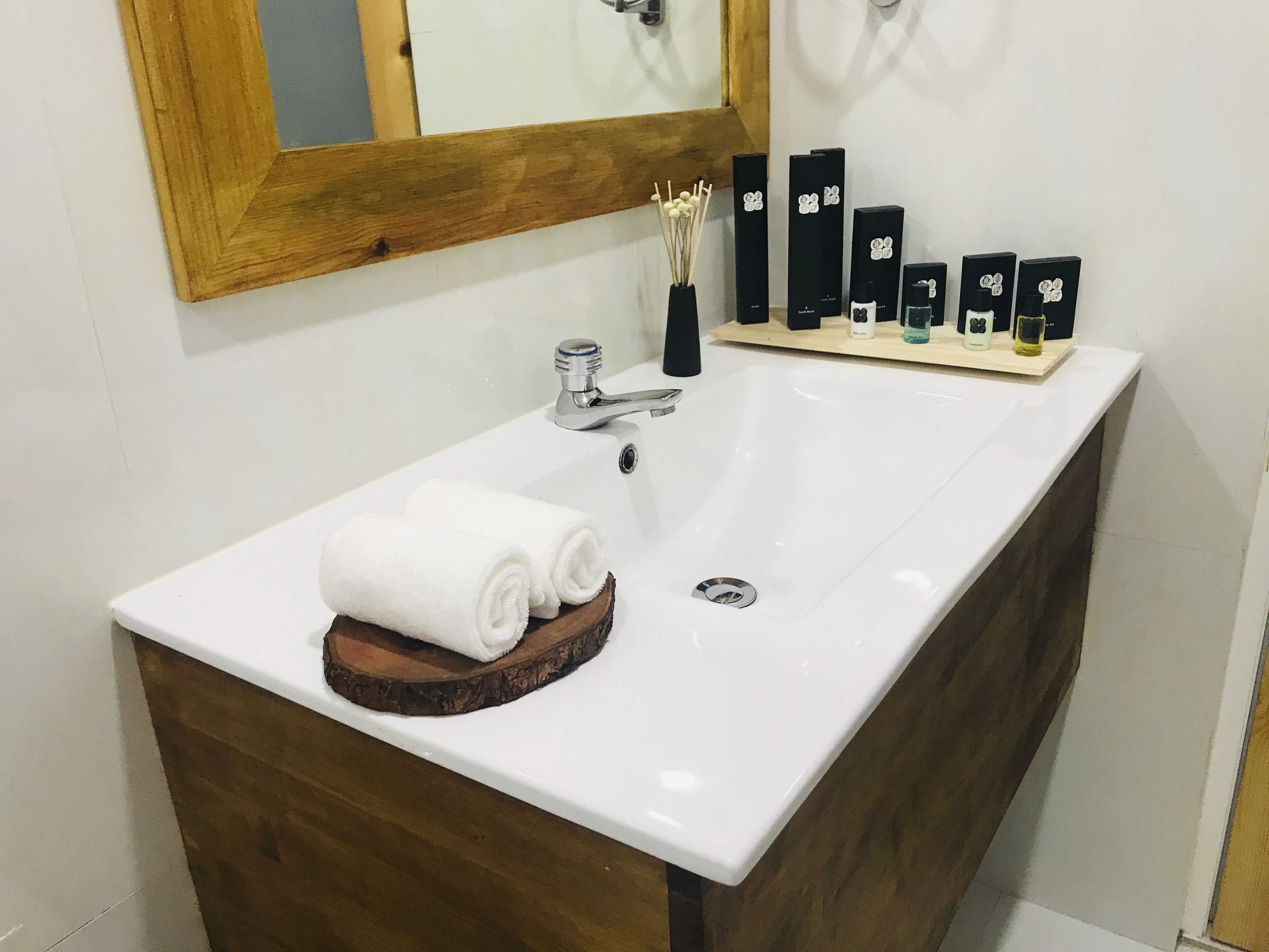A bathroom with a white sink, wooden vanity, and a mirror.