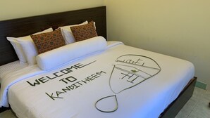A neatly made bed with a welcome mat and a towel rack.