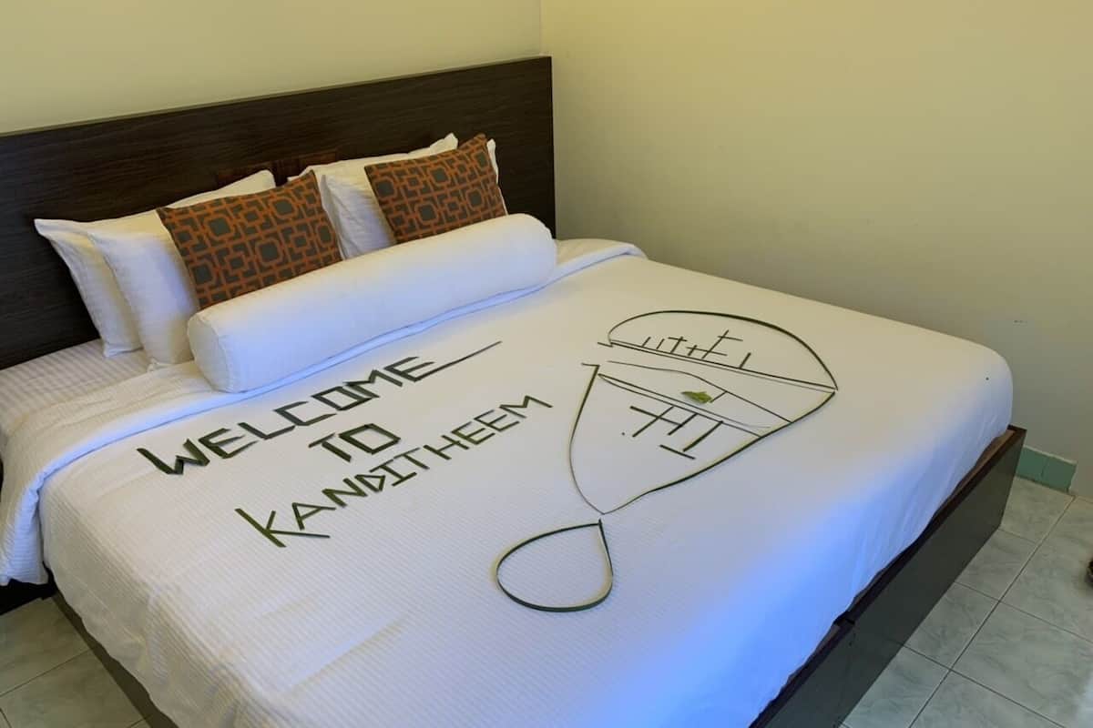 A neatly made bed with a welcome mat and a towel rack.